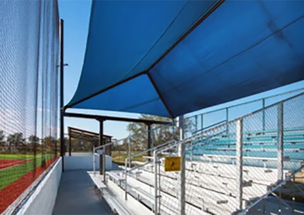 Blue shade canopy over metal bleachers at baseball field by Superior Recreation of the Carolinas.
