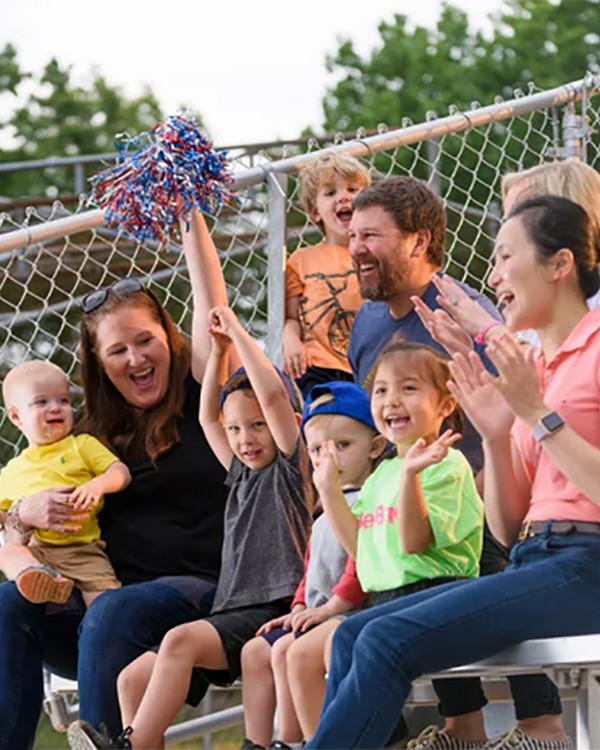 Families cheering on aluminum bleachers installed by Superior Recreation of the Carolinas at a community sports field.