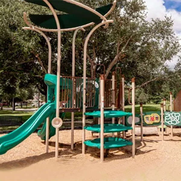 Green playground with slides and shade canopy installed by Superior Recreation of the Carolinas.