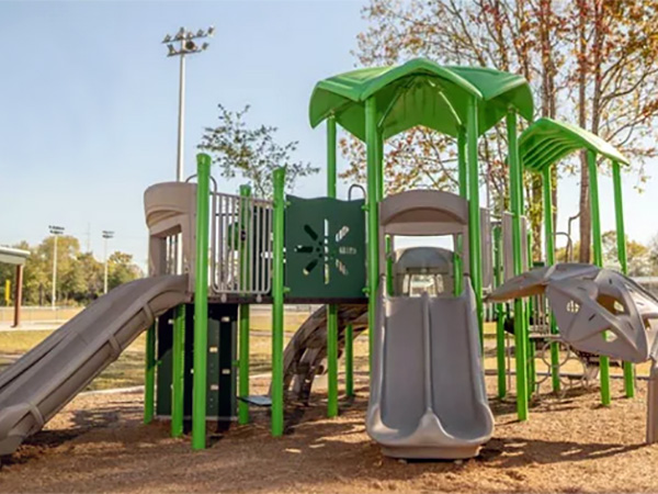 Modern green and gray playground with leaf-shaped canopy roofs and multiple slides.