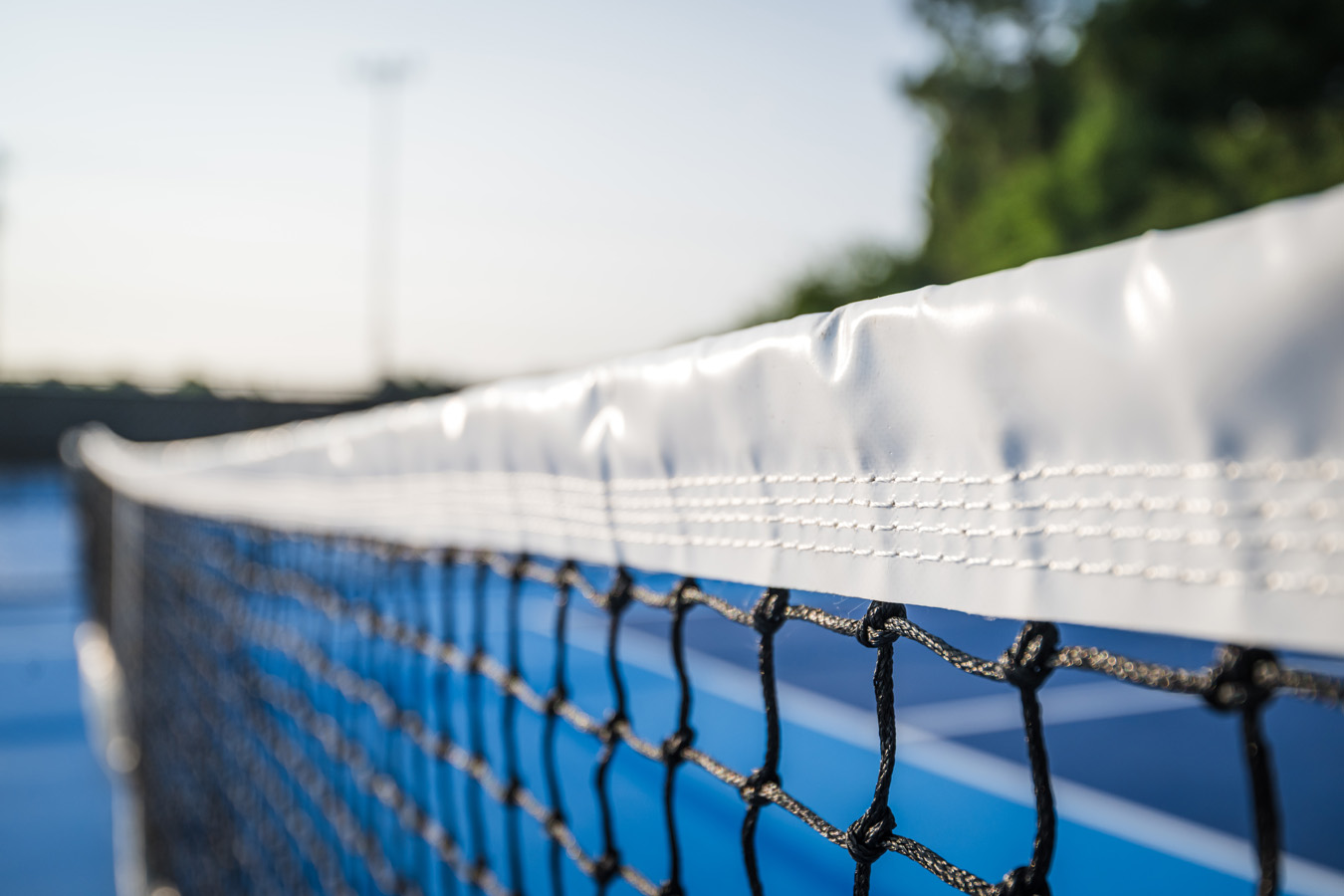 Close-up of pickleball net on outdoor blue courts in Burlington NC.