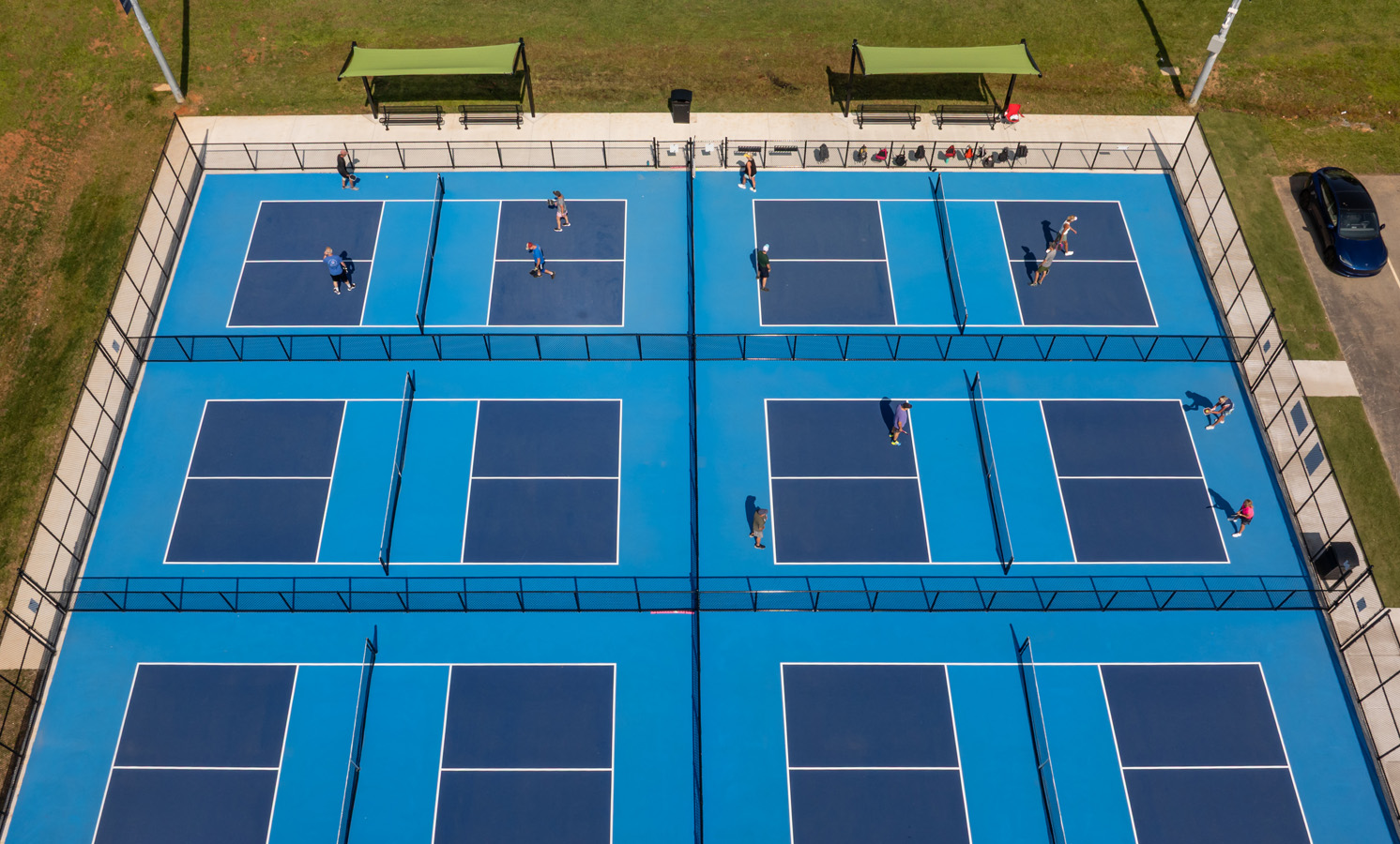 Aerial view of players competing on the bright blue pickleball courts at Fairchild Pickleball & Tennis in Burlington, NC.