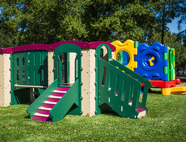 SR Carolinas toddler play structure with green and purple slides on playground turf in The Carolinas