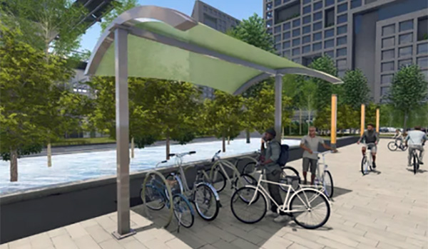 Bike racks with protective green shade structure in an urban community setting.