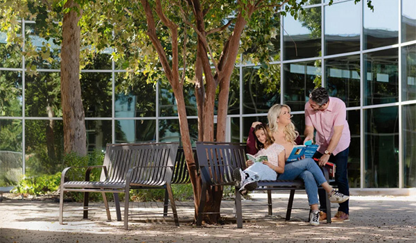 Family enjoying shaded outdoor benches under trees at a community park built by Superior Recreation.