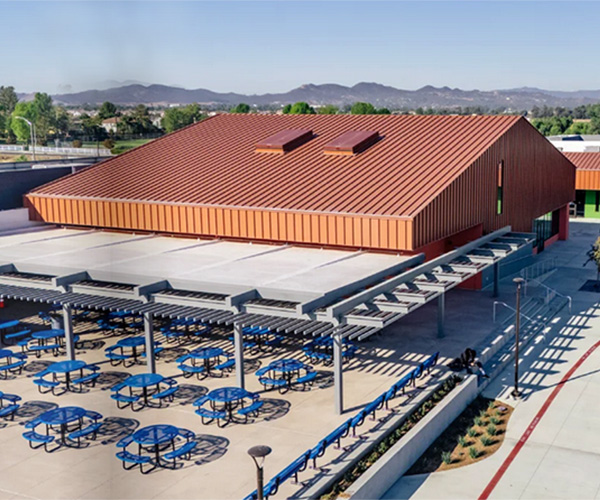 School courtyard with blue picnic tables and steel pergola shade structures installed by Superior Recreation.