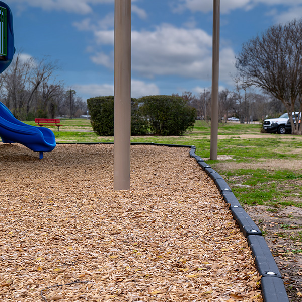 Wood fiber playground mulch with accessible surfacing beneath a blue slide in a public park