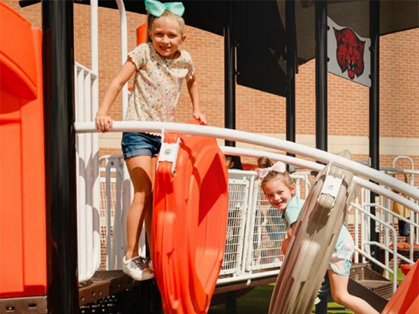 Children playing on orange playground climbing structure at a North Carolina community park.